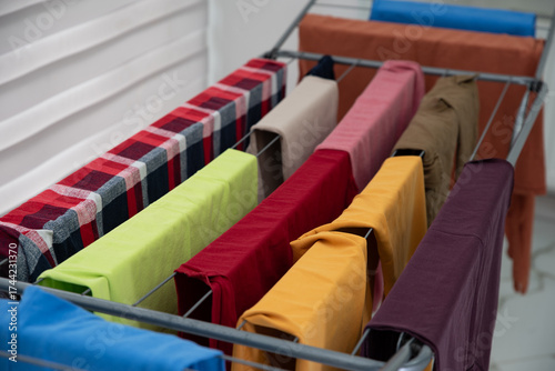 Valokuva Colorful clean laundry drying on metal rack indoors, concept of clean home and f