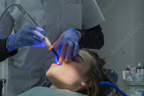 Dentist performing a dental treatment using a laser on a patient in a modern clinic setting