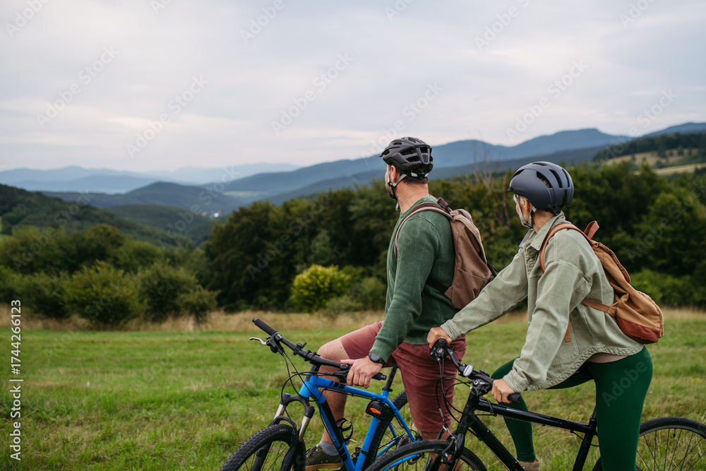 Obraz premium Couple cycling together in nature, smiling and enjoying outdoor adventure.