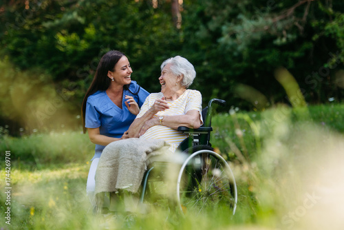 Home nurse taking care of elderly woman in wheelchair.