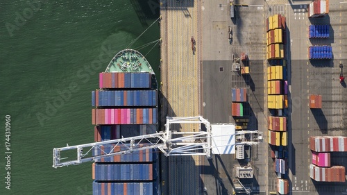 Oakland, United States - 02 September 2025: Aerial view of a colossal cargo ship, a symphony of vibrant containers contrasting with the dark, still waters.