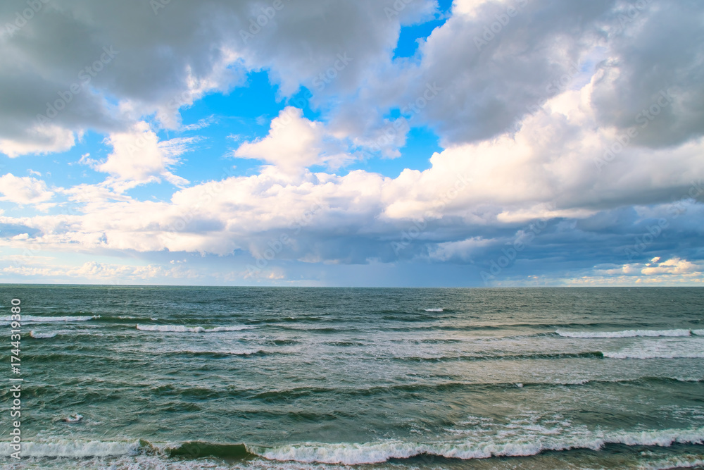 Fototapeta premium Blue sky with clouds over the sea. Calm landscape on the theme of travel and seaside recreation.