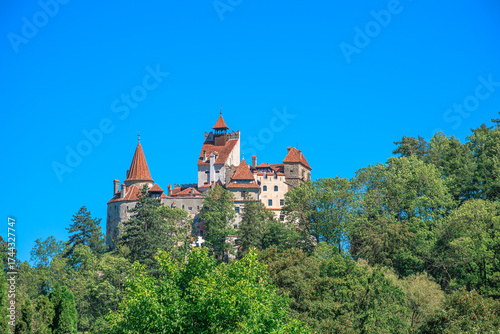 Bran Castle, famous for its connection to Dracula, standing prominently on a forested hillside, attracting tourists to its medieval architecture and historical significance in Romania, Transylvania