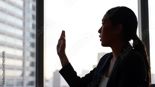 Silhouette of a Businesswoman by the Window - A Moment of Reflection.