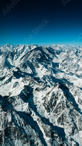 Wide Aerial Panorama of Fully Snow-Capped Andes Mountains Under a Bright Clear Blue Sky from Airplane Window