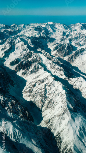 Wide Aerial Panorama of Fully Snow-Capped Andes Mountains Under a Bright Clear Blue Sky from Airplane Window