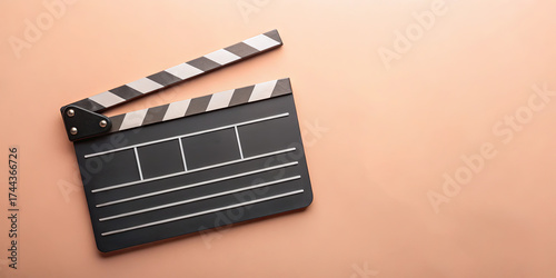 A classic clapperboard rests on a smooth surface, symbolizing film production. It features traditional black and white colors along with a blank slate for scene and take information