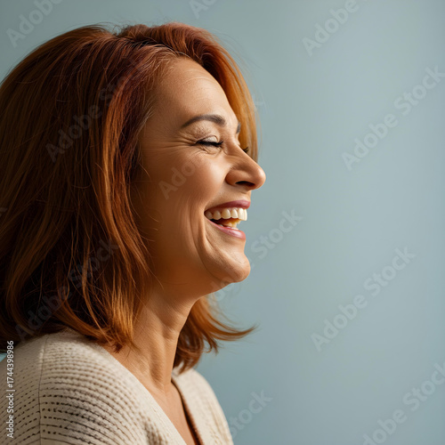 studio profile portrait of a middle-aged redheaded woman laughing