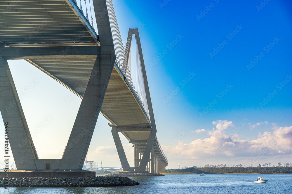 Obraz premium Sailing boat under the Arthur Ravenel Jr. Bridge is a cable-stayed bridge over the Cooper River in South Carolina, US, connecting downtown Charleston to Mount Pleasant