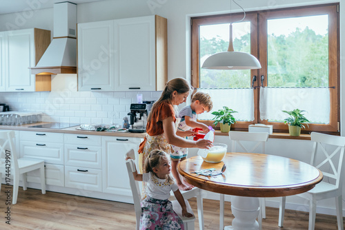 Tableau sur toile Children helping mother prepare breakfast in sunny autumn kitchen