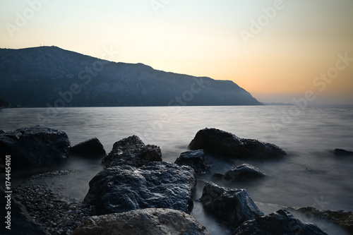 Rocky Seashore at Sunset with Soft Waves and Long Exposure Effect