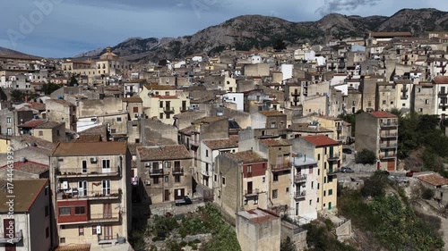 Aerial drone view of Polizzi Generosa, a picturesque Sicilian mountain town perched on rocky cliffs showcasing traditional stone buildings and panoramic views of the Madonie Mountains, Sicily, Italy
