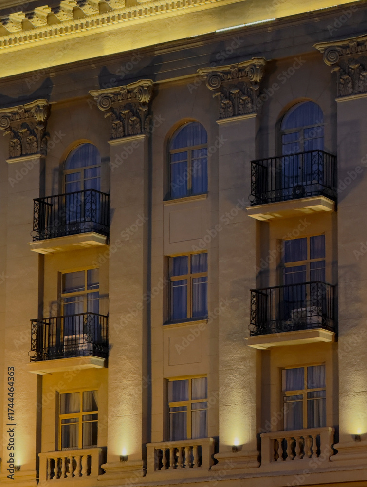 Fototapeta premium Warm lights illuminate the ornate balconies and windows of a historic building at night
