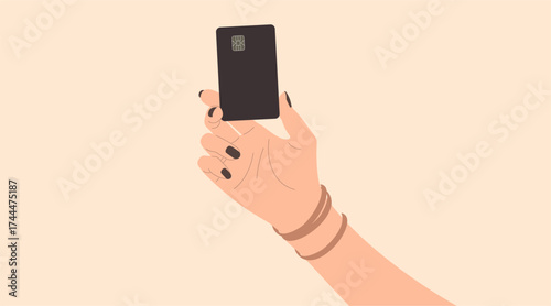 A hand with black nail polish holds a black card vertically, featuring a silver chip, indicative of a credit or debit card. 