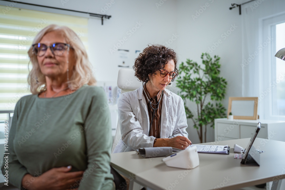Obraz premium mature female doctor analysis patients file during the review at medical clinic