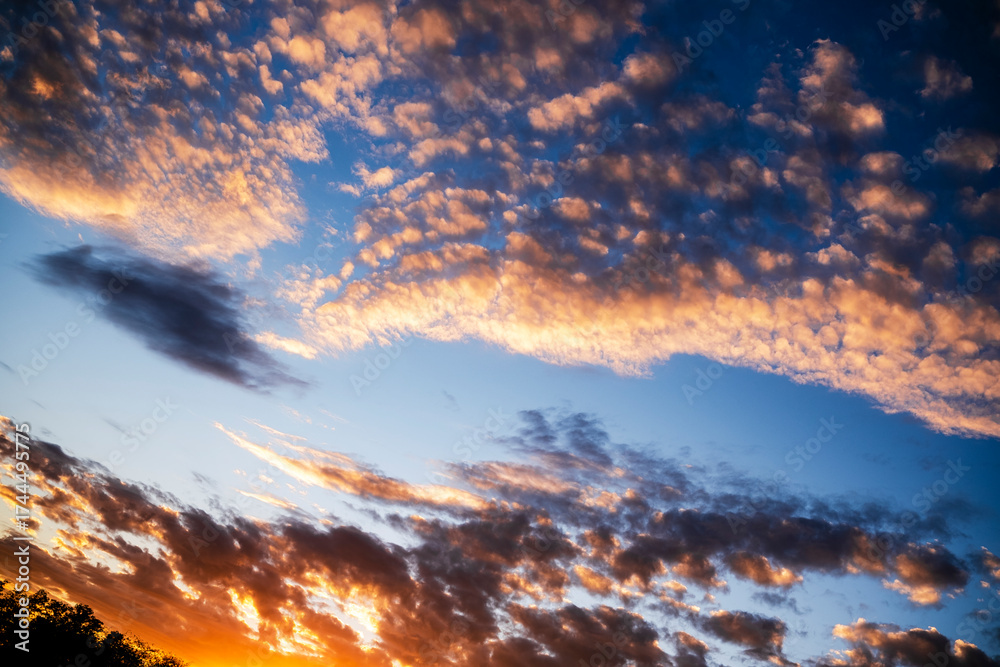 Fototapeta premium Colorful sunset sky filled with clouds over a serene landscape displaying nature's beauty at dusk