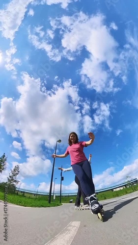 Two Caucasian women roller skating in a park. 