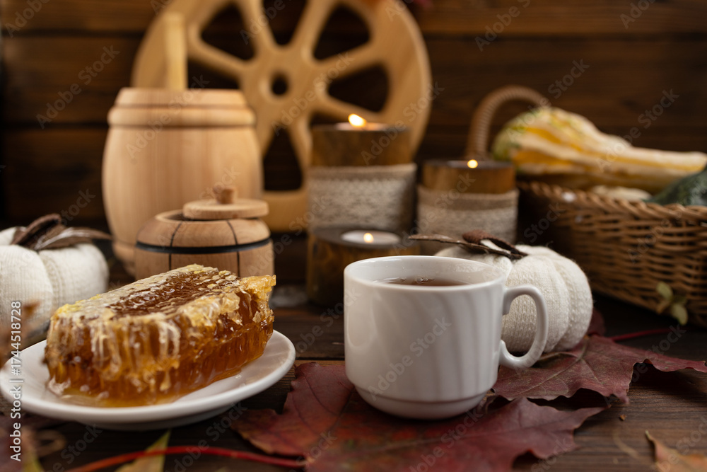 Fototapeta premium lose-up of a honeycomb on a white plate surrounded by a wooden barrel and a cup. a warm and rustic atmosphere. Bee honey.