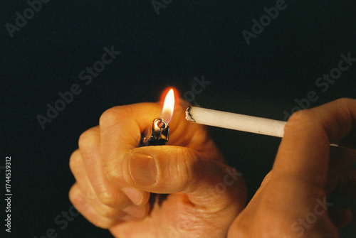 a man lighting a cigarette with a lighter in the dark, 35mm