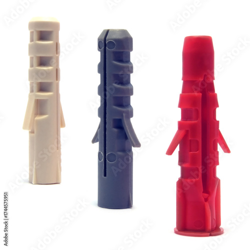 Plastic dowels, colorful red, ivory white, dark blue grey wall plugs, hollow nylon anchors, large detailed isolated macro closeup, blank empty copy space background