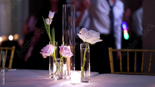 slow motion of table decorations at a party wedding reception with people dancing in the background at night