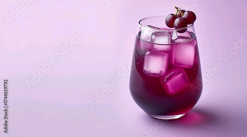 Rounded glass of blackcurrant juice with ice cubes and fruit garnish on pastel violet background