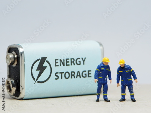 Mini toy of action figure at table with blurred background. Miniature photography concept design. Minifigure of engineer character with battery storage mobile.