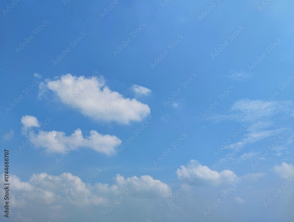 Naklejka premium clear blue sky with a few clouds. The sky is very bright and the clouds are scattered throughout 