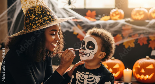 Black mother doing makeup for son for in costume skeleton Halloween. Happy african american family preparing for Halloween celebration.	