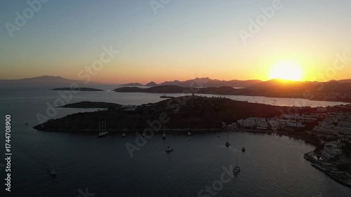 Bodrum, Turkey: Aerial footage of dramatic sunset over Bodrum peninsula, beach city and resort in Turkey with sillhouette of boats in the water 
