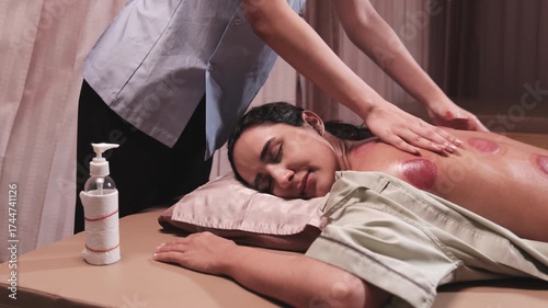 Hispanic female patient is oil massaged for muscle relaxation after cupping therapy by physiotherapist's hand, oriental traditional medical healing at spa clinic, and healthcare wellness lifestyle.