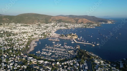 Bodrum, Turkey: Aerial drone footage of waterfront Marina and Castle in Bodrum with mountain in the background on sunny day. Holiday destination in Turkey. Taken with orbiting motion