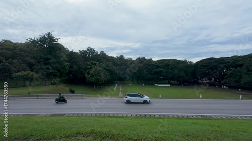 Roadside View with Moving Vehicles and Lush Green Park