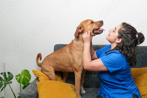 Woman vet comforting a happy brown dog on a sofa, showing care and pet friendship