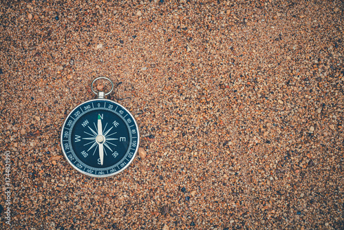 Navigation compass resting on beach sand.