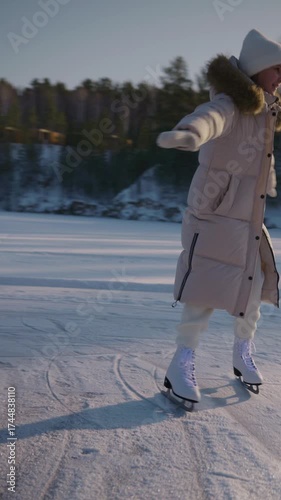 Young girl skates on the icy lake in sunny winter day. Winter activities on Christmas vacation. Vertical video 4k.