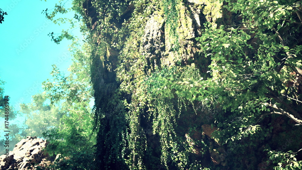 Obraz premium Sunlight filters through vibrant foliage as vines cascade down a rugged cliffside. This tranquil scene captures the natural beauty of a peaceful outdoor spot.