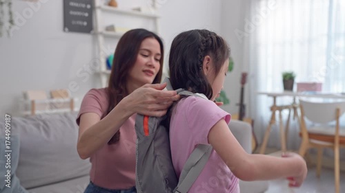 Asian beautiful mother prepare school backpack to young daughter at home. 