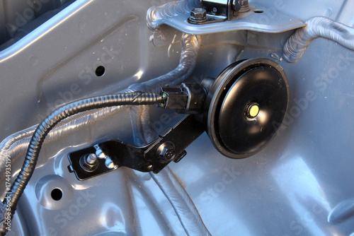 Car horn under the hood. Close-up of  modern car horn. An electric horn in engine compartment of modern car. Car engine detail with a focus on the black metal horn