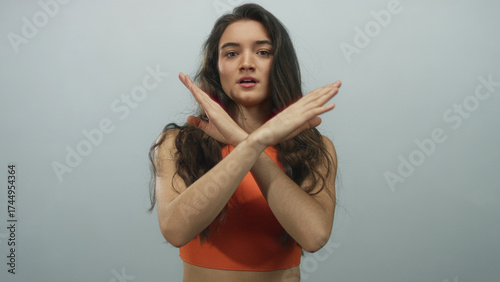 Obraz na plátne Young woman crosses bare arms in denial gesture in studio under soft lighting with stern expression; rejection