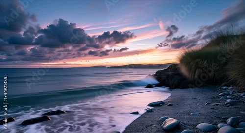 Serene ocean waves gently wash over a tranquil beach at twilight, with dramatic clouds painting the sky.