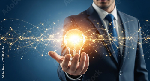 Businessman holding a glowing light bulb, representing innovation and connection in a network.