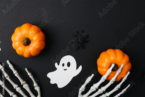 Halloween decoration: pumpkins, ghost, spiders, skeleton hands on black background top view