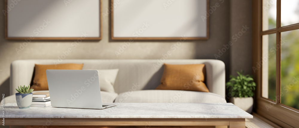 Fototapeta premium Laptop with book and pot plant on marble table across sofa with cushion aside window in living room.