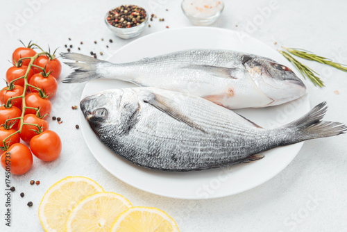 Raw dorado fish with tomatoes lemon and spices on white background