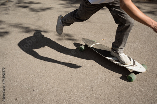 Unrecognizable male skateboarder moving his board by pushing off with one foot