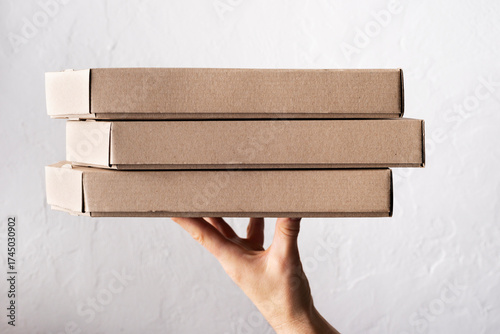 Caucasian male hands hold three pizza boxes side view with copy-space