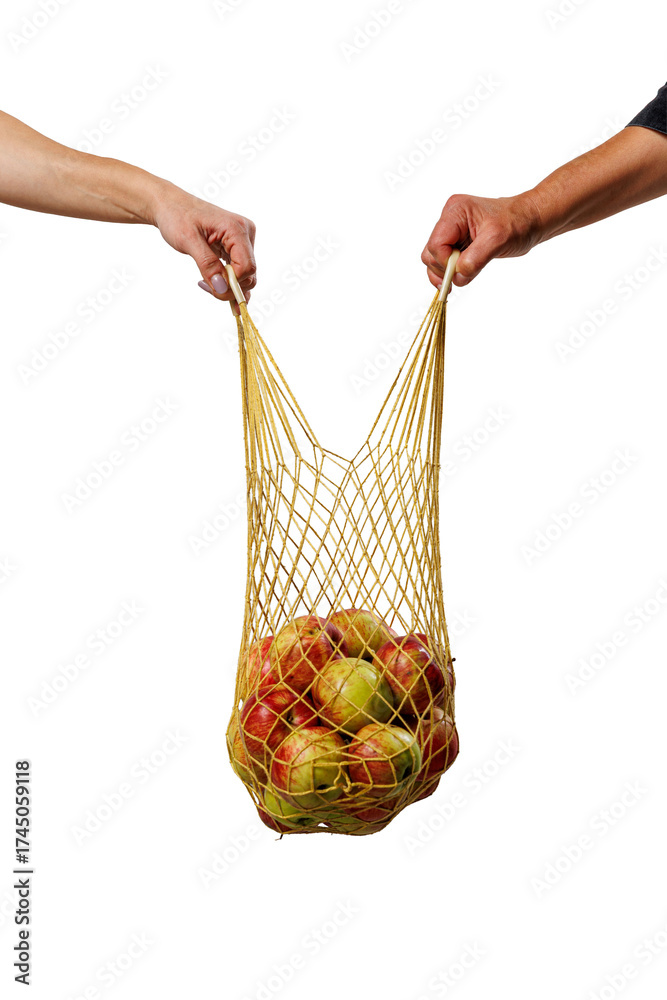 Obraz premium Two hands holding a mesh bag full of apples, symbolizing cooperation, eco-friendly living, and sustainable habits through reusable shopping and shared values