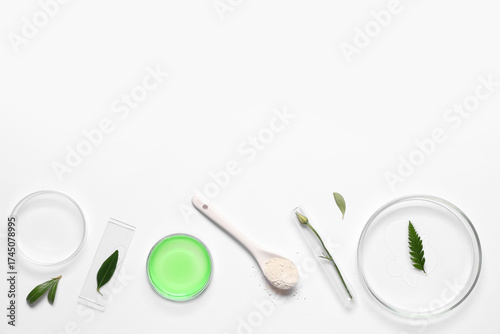 Petri dish with plant sample and laboratory equipment on white background