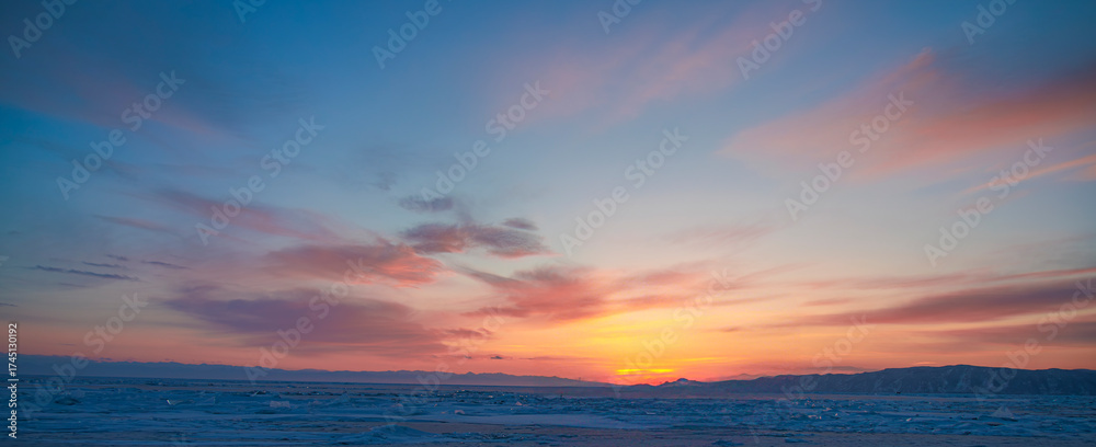 Fototapeta premium sunset over the ocean with soft clouds and golden sunlight reflecting on the sea surface. Peaceful seascape and natural sky gradient from blue to orange,